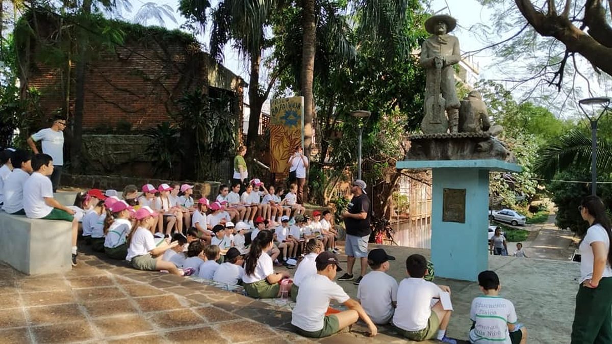 Grupo escolar escuchando a su guía frente al monumento del mensú, en la Bajada Vieja de Posadas